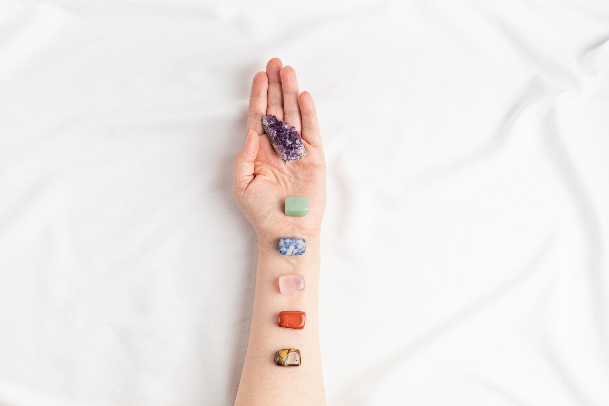 Healing reiki chakra crystals on woman's hands. Gemstones for wellbeing, meditation, relaxation